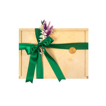 Pine wooden gift box with a satin green bow and dried seasonal greenery