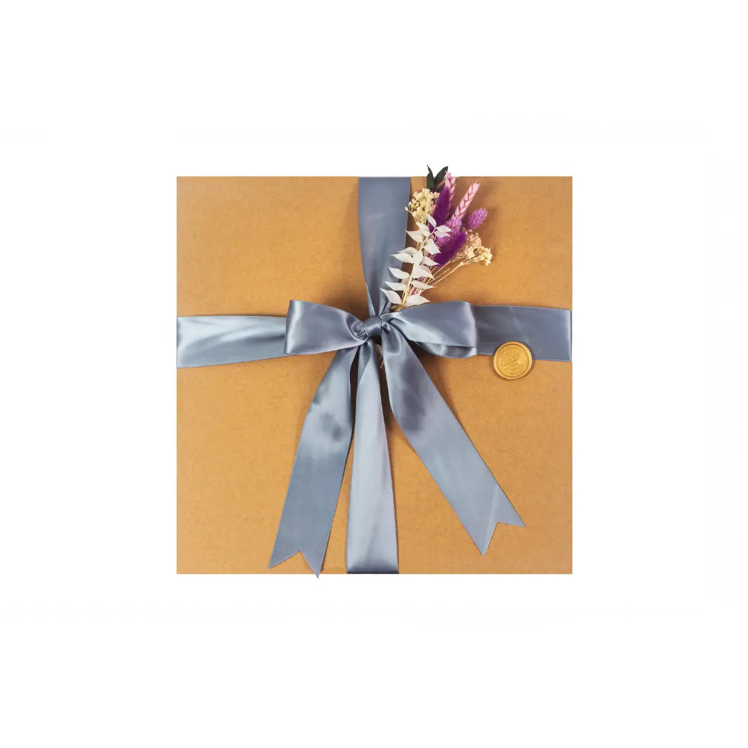 Exterior of a medium sized kraft  gift box with a silver ribbon and seasonal greenery  