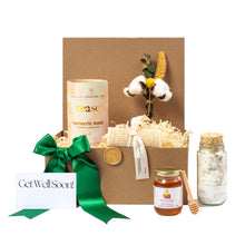 Eco-friendly Get Well Soon gift basket with turmeric tonic, cotton flower bouquet, honey jar with dipper, natural bath salts in corked glass bottle, and sustainable packaging with green ribbon and personalized card. Curated with locally sourced products from small businesses for a thoughtful, plastic-free recovery gift.