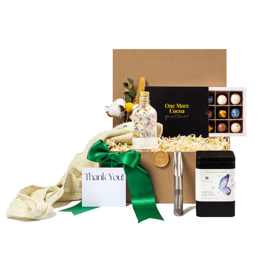 Luxury eco-friendly gift basket featuring locally-sourced products, including gourmet chocolates, herbal tea, bath salts, a sustainable tea infuser, and a soft cotton blanket. Thoughtfully curated with a 'Thank You' note, green ribbon, and natural packaging. Ideal for corporate gifts, client appreciation, housewarming, or employee recognition. Toronto-based, women-owned small business promoting sustainability and zero-waste solutions